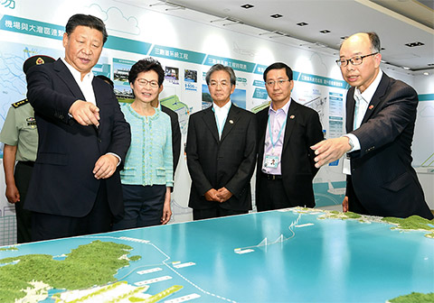 模型を見ながら、香港政府のインフラ投資について説明を受ける習近平国家主席（写真・左端）